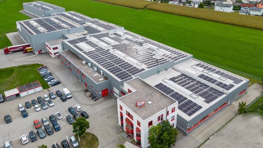 Luftaufnahme des Promotech-Gebäudes mit Solaranlagen, umgeben von Feldern