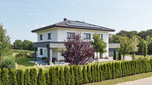 Massives Ziegelhaus mit umlaufender Terrasse Außenansicht mit Hecke