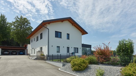 Massivhaus aus Ziegel und Holz mit Wintergarten - Außenansicht mit Einfahrt und Carport