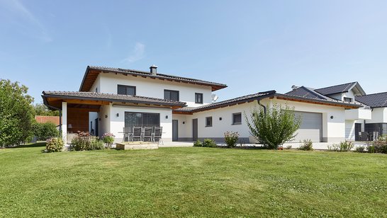 Ansicht eines modernen Einfamilienhauses mit überdachter Terrasse und großem Garten