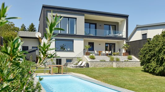 Moderner Holzbau mit Balkon - Gartenansicht mit Pool