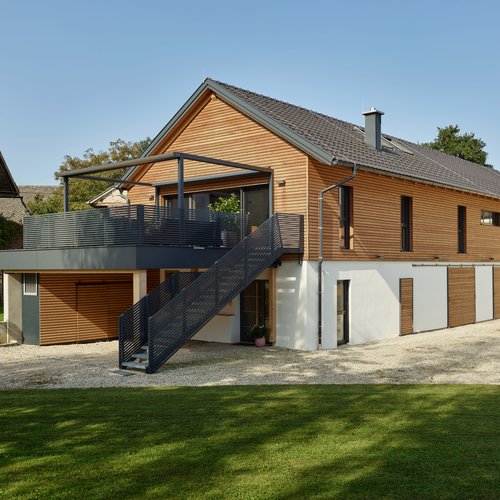Modernes Einfamilienhaus mit Holzverkleidung und einem Außentreppenaufgang zur Terrasse