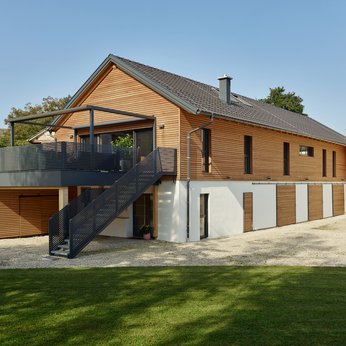 Modernes Einfamilienhaus mit Holzverkleidung und einem Außentreppenaufgang zur Terrasse