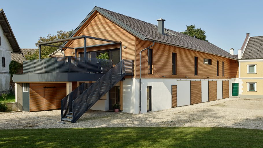 Modernes Einfamilienhaus mit Holzverkleidung und einem Außentreppenaufgang zur Terrasse