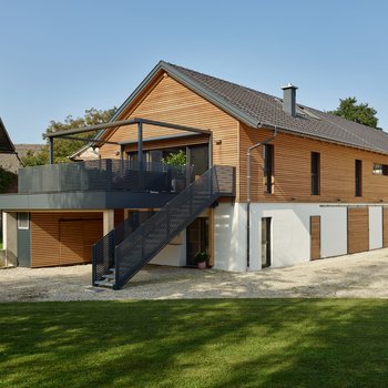 Modernes Einfamilienhaus mit Holzverkleidung und einem Außentreppenaufgang zur Terrasse