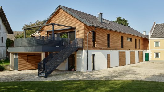 Modernes Einfamilienhaus mit Holzverkleidung und einem Außentreppenaufgang zur Terrasse