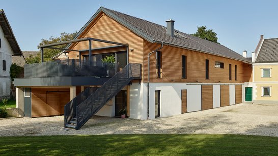 Modernes Einfamilienhaus mit Holzverkleidung und einem Außentreppenaufgang zur Terrasse
