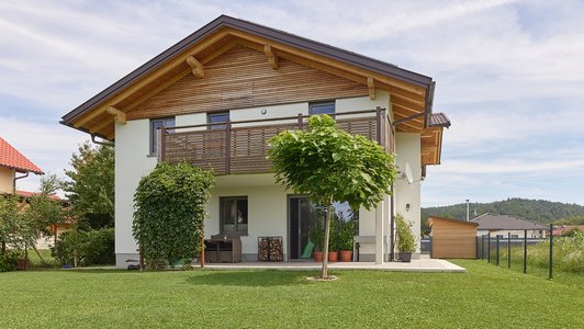 Familienhaus aus Massivholz - Außenansicht mit Garten und Gartenhaus