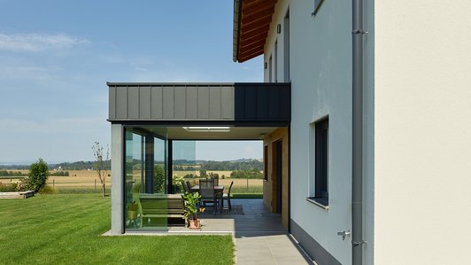 Massivhaus aus Ziegel und Holz mit Wintergarten - Außenansicht vom Wintergarten