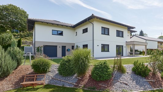 Massives Familienhaus mit Veranda - Außenansicht mit Garten und Büschen