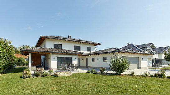 Ansicht eines modernen Einfamilienhauses mit überdachter Terrasse und großem Garten