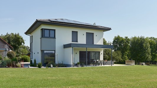 Kompaktes Familienhaus mit Garage - Gartenansicht mit Terrasse