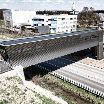 Luftaufnahme der AMAG Austria Fußgängerbrücke über eine Straße, modernes Design mit horizontalen Lamellen