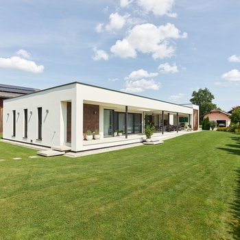 Außenansicht mit einer langen überdachten Terrasse und gepflegtem Rase