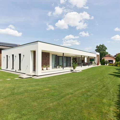 Außenansicht mit einer langen überdachten Terrasse und gepflegtem Rase