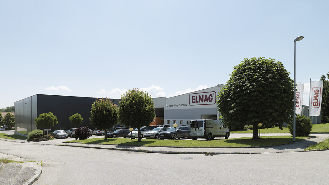 Firmengelände von ELMAG Entwicklungs- und Handels GmbH mit Firmenfahrzeugen und Bäumen