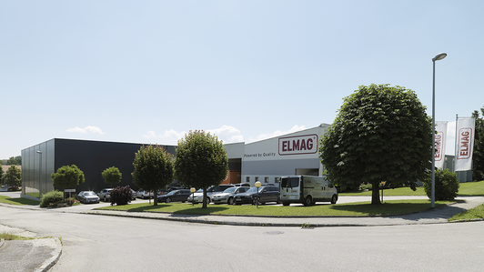 Firmengelände von ELMAG Entwicklungs- und Handels GmbH mit Firmenfahrzeugen und Bäumen