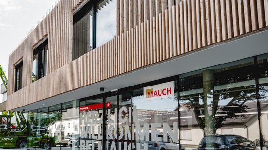 Nahaufnahme des Eingangsbereichs des Mauch Landmaschinen Handels mit ausgestellten Teleskopladern