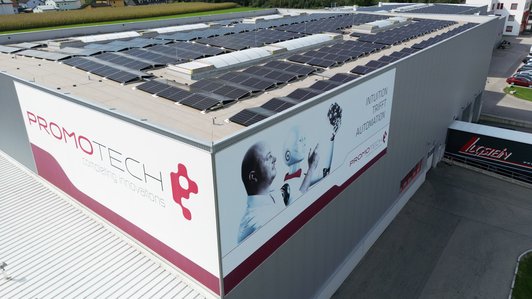 Promotech-Gebäude mit Solaranlagen auf dem Dach, Seitenansicht mit großem Logo