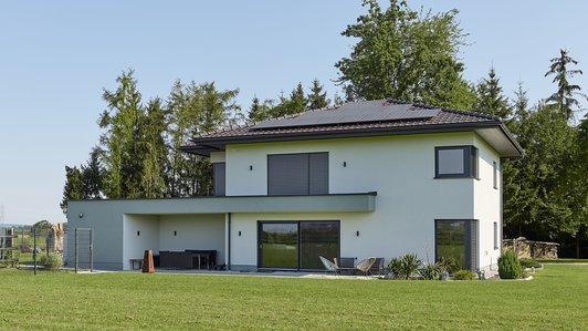 Modernes Massivhaus - Gartenansicht mit Terrasse