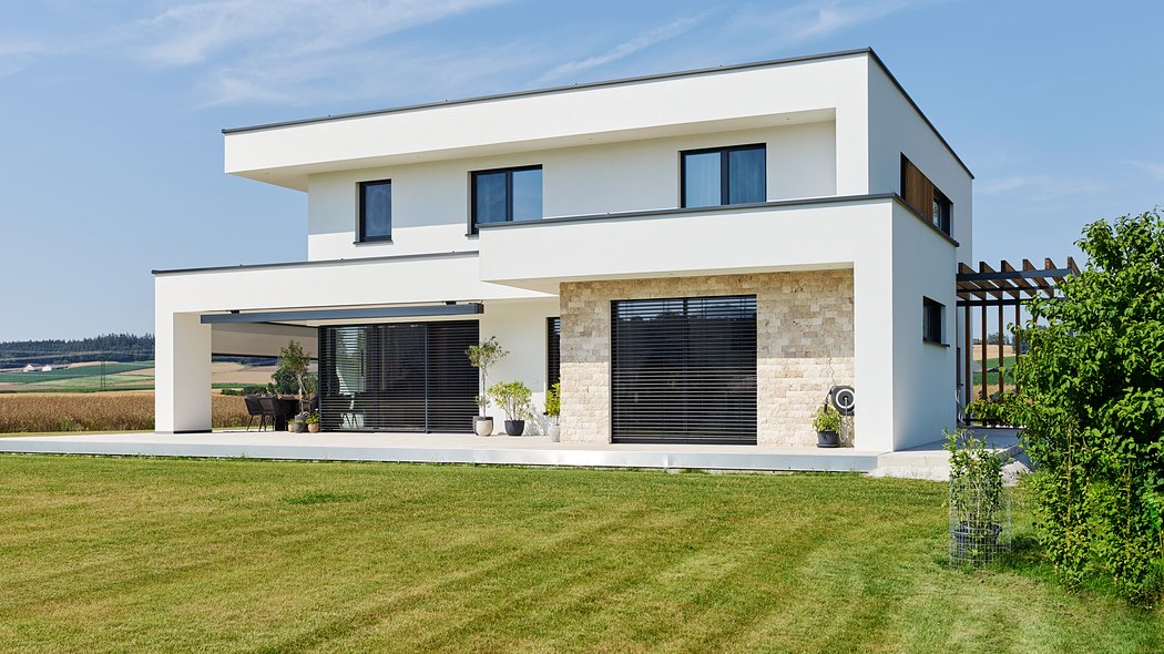 Modernes Massivhaus - seitliche Außenansicht mit Garten 