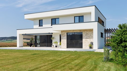 Modernes Massivhaus - seitliche Außenansicht mit Garten 